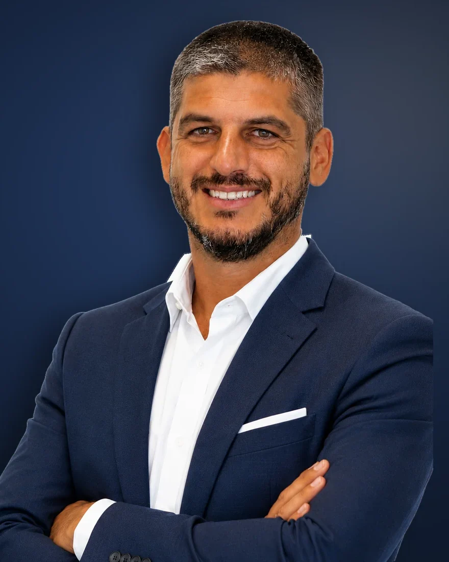 Luca Marzotto, in giacca blu e camicia bianca, sorride a braccia incrociate.